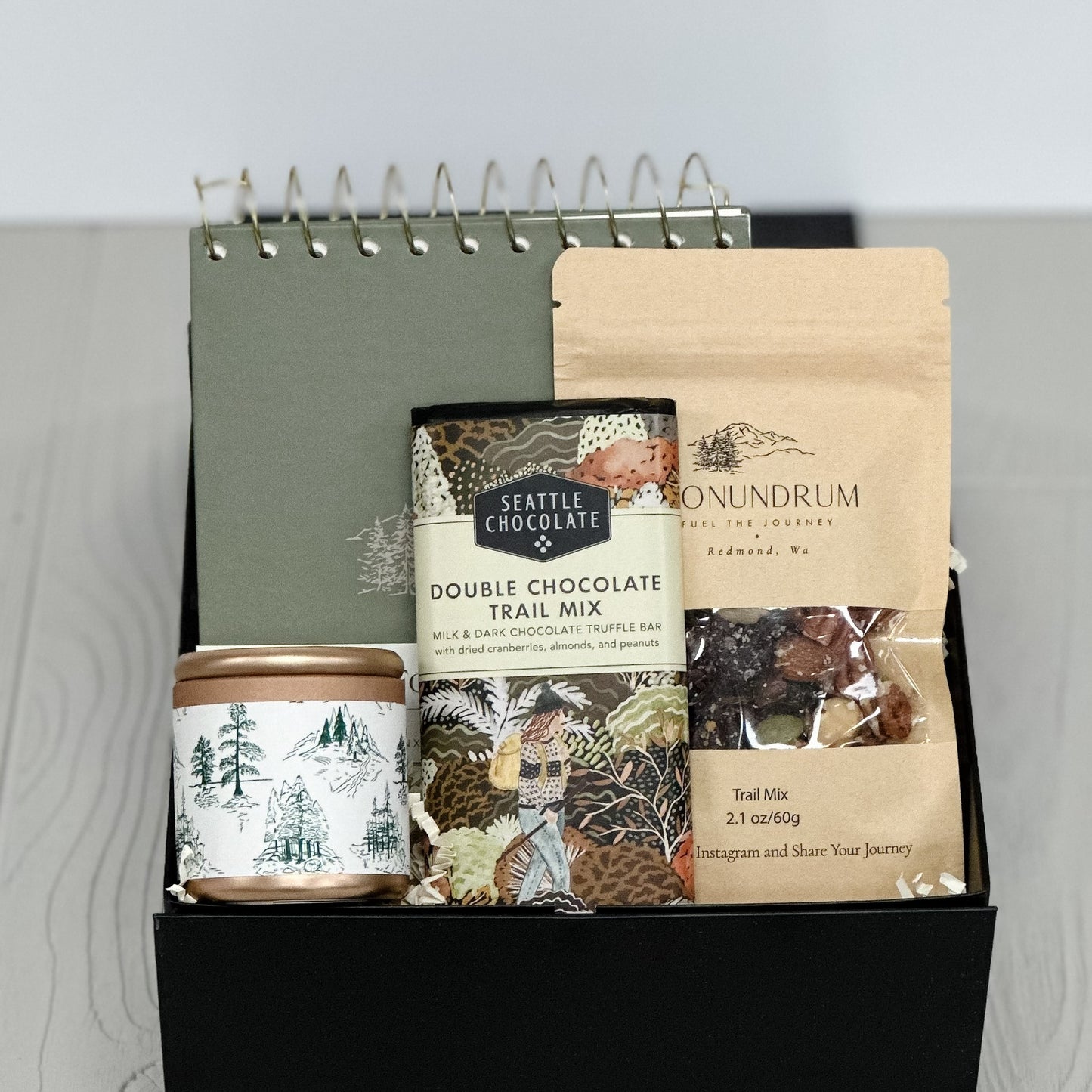 gift box with notebook, trail mix, chocolate and candle all included in our notes and nibbles gift box